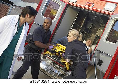 Stock Image - Paramedics and doctor unloading patient from ambulance. Fotosearch