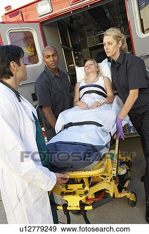 Stock Photo - Paramedics and doctor unloading patient from ambulance. Fotosearch