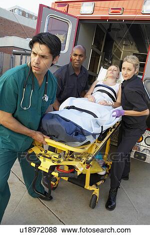 Stock Photo - Paramedics and doctor unloading patient from ambulance. Fotosearch