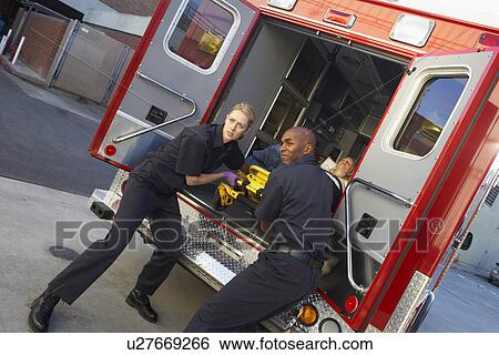 Stock Photograph - Paramedics preparing to unload patient from ambulance. Fotosearch
