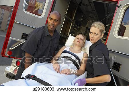 Stock Image - Paramedics unloading patient from ambulance. Fotosearch