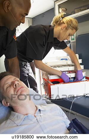 Stock Image - Paramedics with patient in ambulance. Fotosearch