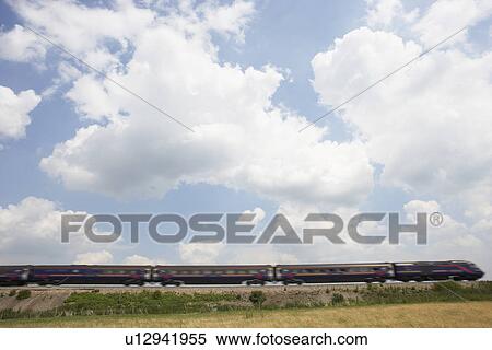 Stock Photography - Passenger Train Moving Beneath A Clouded Sky. Fotosearch