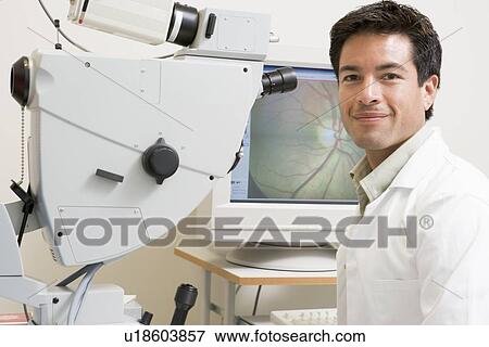 Stock Photo - Portrait Of A Doctor Next To An Eye Exam Machine. Fotosearch