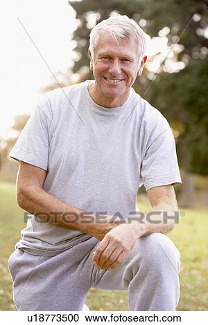Stock Image - Portrait Of Senior Man Crouching In The Park. Fotosearch
