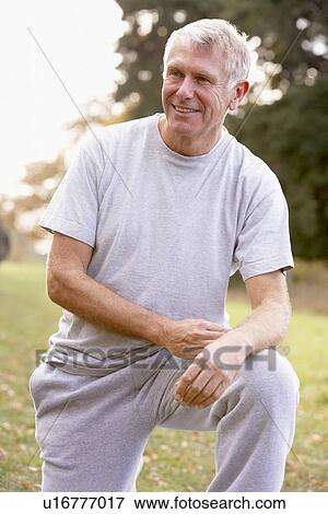 Stock Photo - Portrait Of Senior Man Kneeling In Park. Fotosearch