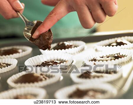 Stock Image - Putting Chocolate Cupcake Mix Into Baking Tin. Fotosearch