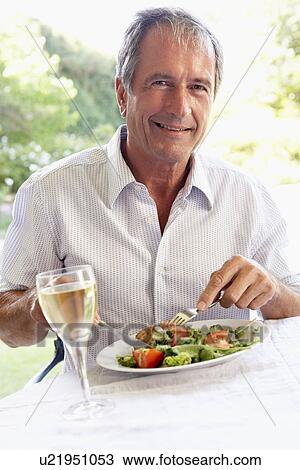 Stock Image - Senior Man Eating An Al Fresco Lunch. Fotosearch