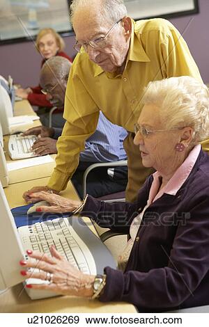 Stock Photo - Senior man helping senior woman to use computer. Fotosearch