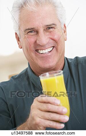 Stock Photo - Senior Man Holding A Glass Of Fresh Orange Juice, Smiling At The Camera. Fotosearch