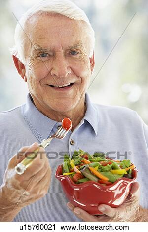 Stock Image - Senior Man Smiling At Camera And Eating Salad. Fotosearch