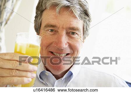 Stock Photograph - Senior Man Smiling At Camera And Drinking Orange Juice. Fotosearch