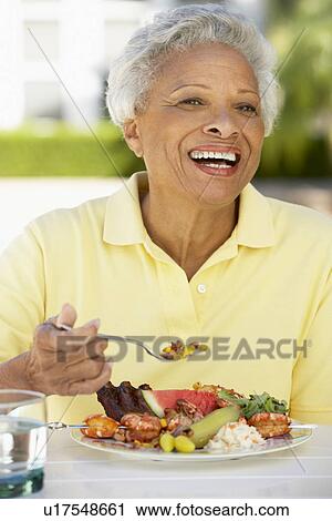Stock Image - Senior Woman Dining Al Fresco. Fotosearch
