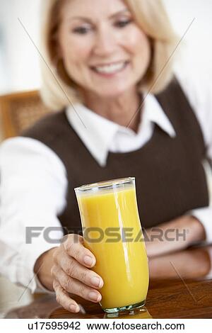 Stock Image - Senior Woman Drinking A Glass Of Fresh Orange Juice. Fotosearch