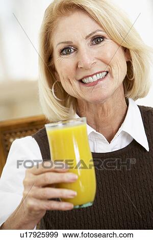 Stock Photo - Senior Woman Drinking A Glass Of Fresh Orange Juice. Fotosearch