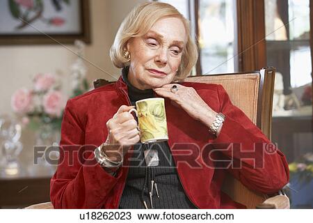 Stock Image - Senior woman drinking hot beverage. Fotosearch