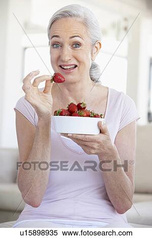 Stock Photography - Senior Woman Eating A Bowl Of Strawberries. Fotosearch