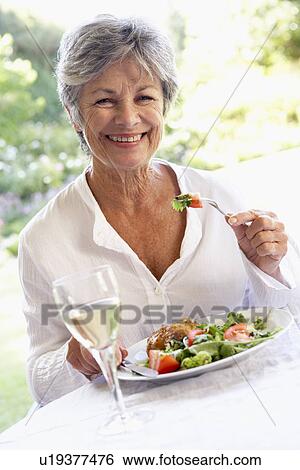 Stock Photograph - Senior Woman Eating An Al Fresco Lunch. Fotosearch