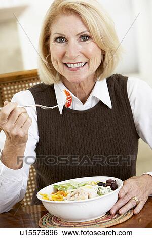 Stock Photograph - Senior Woman Eating Dinner, Smiling At The Camera. Fotosearch