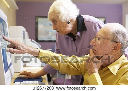 Stock Image - Senior woman helping senior man use computer. Fotosearch