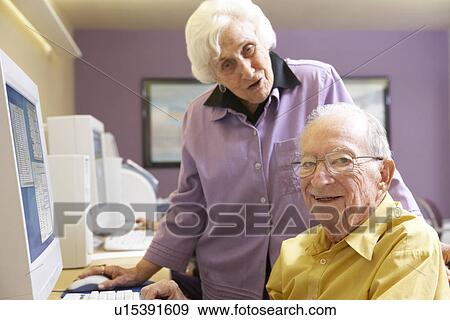 Stock Photo - Senior woman helping senior man use computer. Fotosearch
