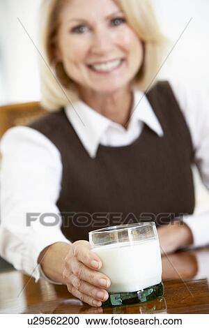 Stock Image - Senior Woman Holding A Glass Of Milk, Smiling At The Camera. Fotosearch
