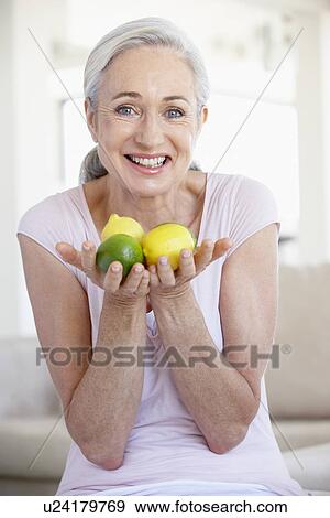 Stock Photo - Senior Woman Holding Fruit And Smiling At The Camera. Fotosearch