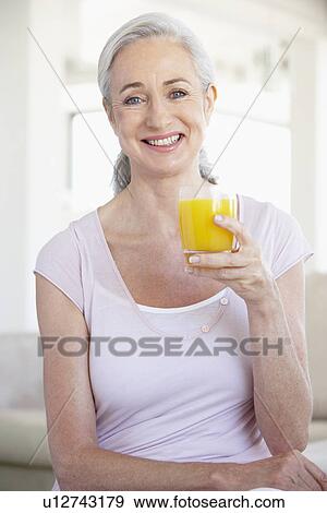 Stock Photo - Senior Woman Holding Orange Juice And Smiling At The Camera. Fotosearch