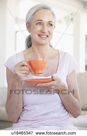 Stock Photo - Senior Woman Holding Tea And Smiling At The Camera. Fotosearch