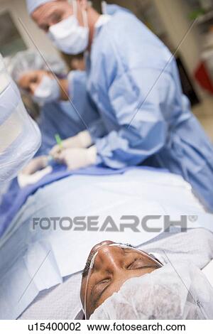 Stock Image - Surgeons Operating On Patient. Fotosearch