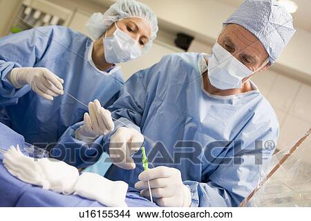 Picture - Surgeons Preparing Equipment For Surgery. Fotosearch