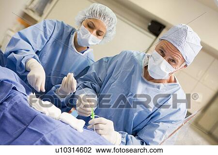 Stock Image - Surgeons Preparing Equipment For Surgery. Fotosearch
