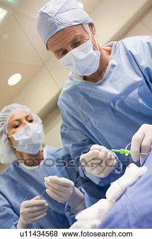 Stock Photo - Surgeons Preparing Equipment For Surgery. Fotosearch