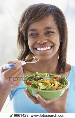 Stock Image - Teenage Girl Holding A Bowl Of Salad And Smiling At The Camera. Fotosearch