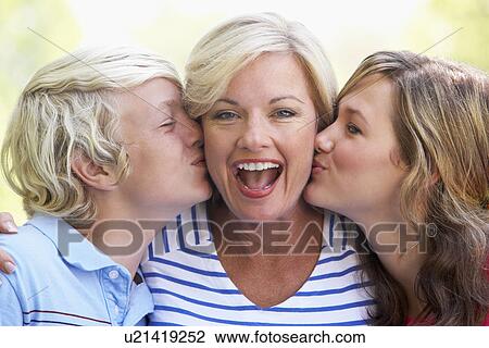 Stock Image - Woman Being Kissed By Her Teenage Children. Fotosearch