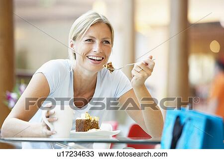 Stock Image - Woman Eating A Piece Of Cake At The Mall. Fotosearch