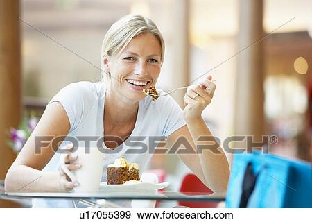 Stock Photo - Woman Eating A Piece Of Cake At The Mall. Fotosearch