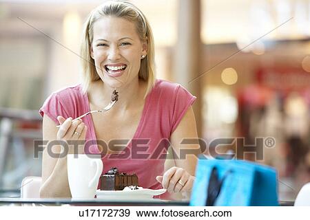 Stock Photo - Woman Eating A Piece Of Cake At The Mall. Fotosearch