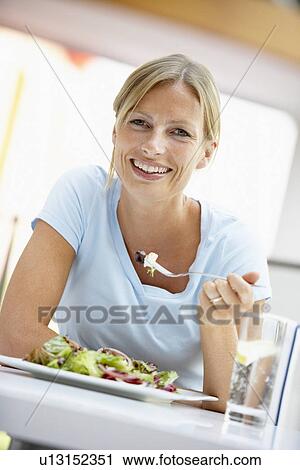 Stock Image - Woman Eating Lunch At A Cafe. Fotosearch