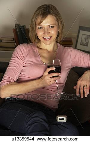 Picture - Woman Relaxing With Glass Of Wine Watching Television. Fotosearch