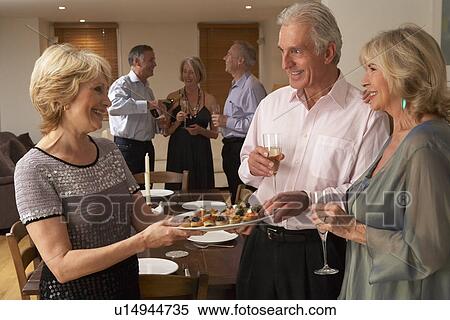 Stock Photography - Woman Serving Hors D'oeuvres To Her Guests At A Dinner Party. Fotosearch