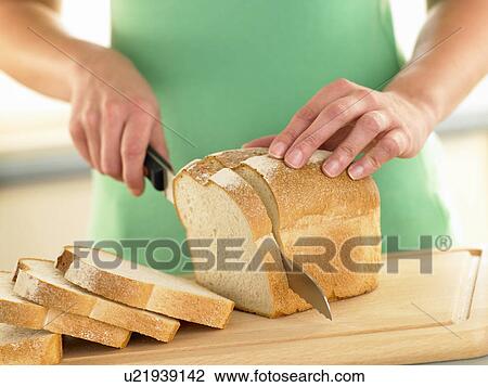 Stock Image - Woman Slicing A Loaf Of White Bread. Fotosearch