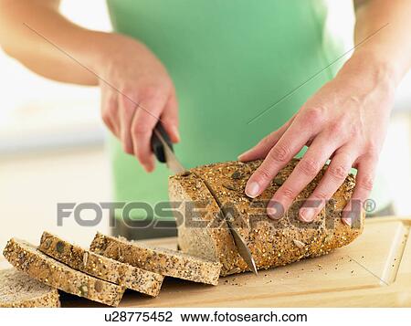 Stock Image - Woman Slicing Mixed Grain Bread. Fotosearch