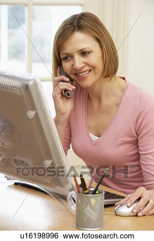 Stock Photograph - Woman Using Computer And Talking On Phone. Fotosearch