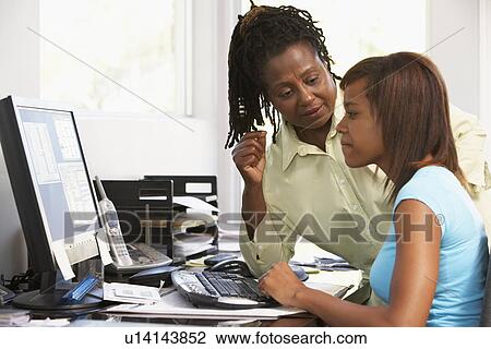 Stock Image - Woman Watching Her Daughter Use A Computer. Fotosearch