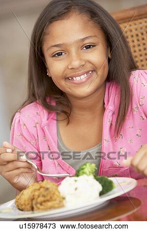 Stock Image - Young Girl Enjoying A Meal At Home. Fotosearch