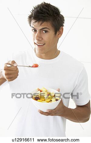 Stock Image - Young Man Eating Fresh Fruit Salad. Fotosearch