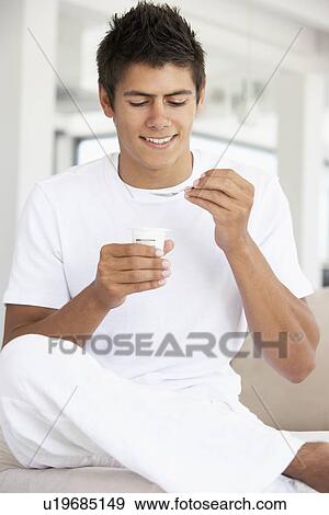 Young Man Eating Yogurt View Large Photo Image Stock Photo - Young Man Eating Yogurt. Fotosearch