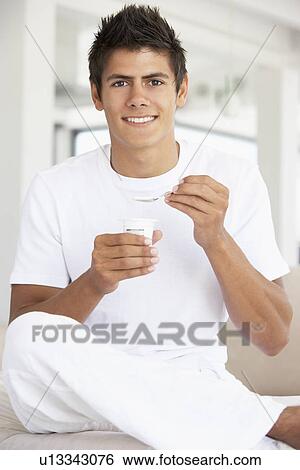 Stock Photograph - Young Man Eating Yogurt. Fotosearch