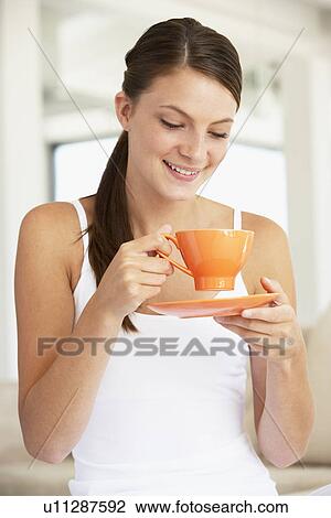 Stock Image - Young Woman Drinking Out Of An Orange Cup. Fotosearch